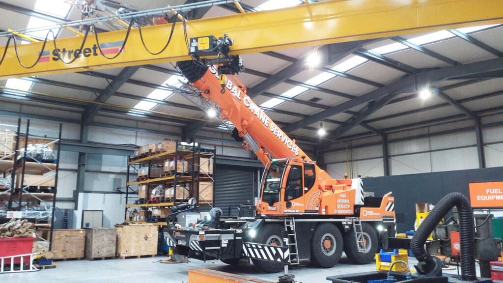 overhead crane installation using mobile crane to position bridge beam inside industrial facility
