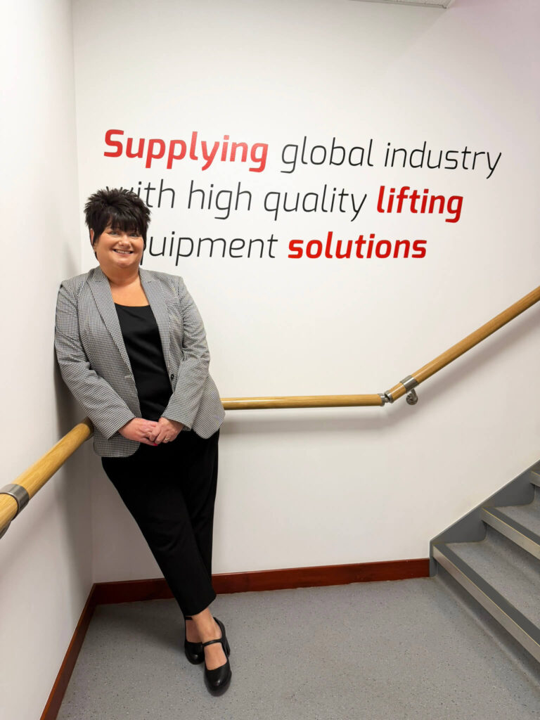 Person standing on a stairwell beside a wall with branded company messaging
