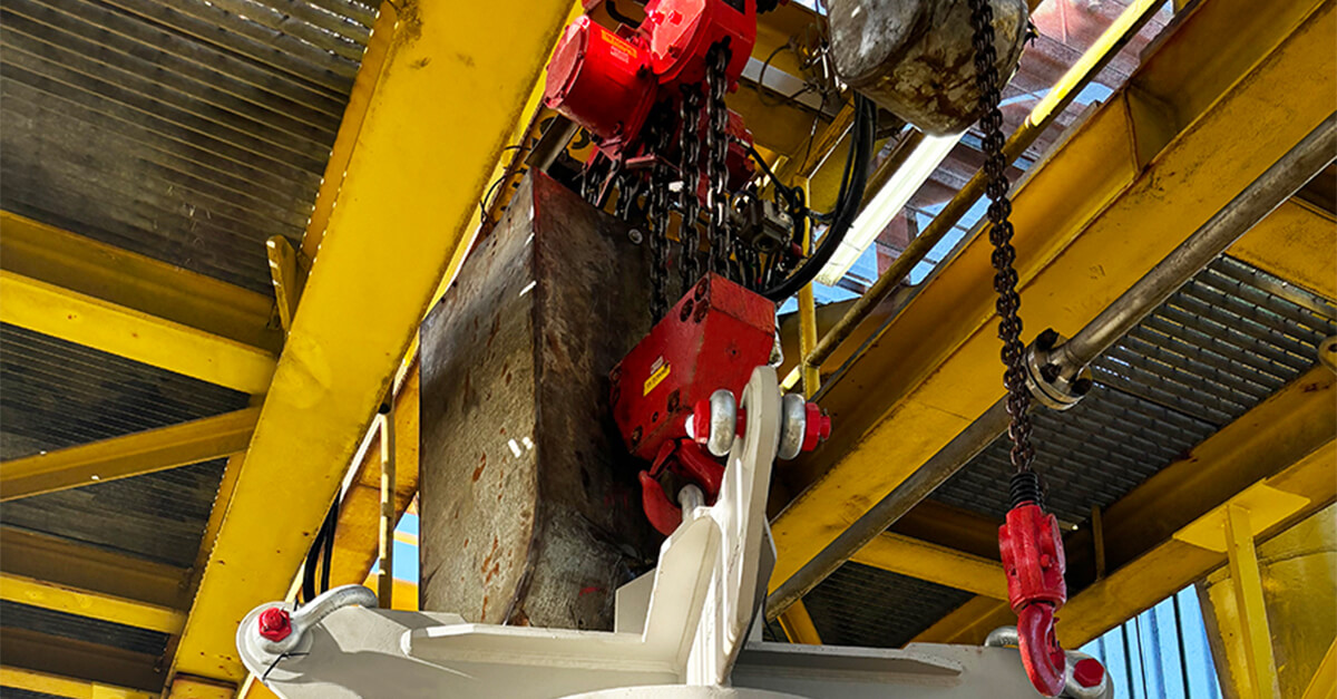Red air hoist lifting heavy component in industrial offshore maintenance environment